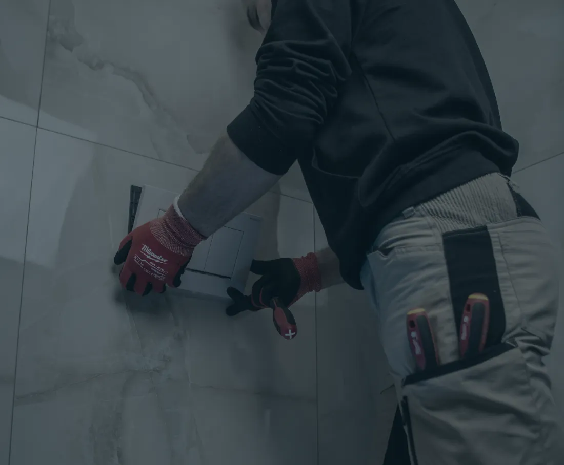 Plumber fitting a flush plate to a tiled wall